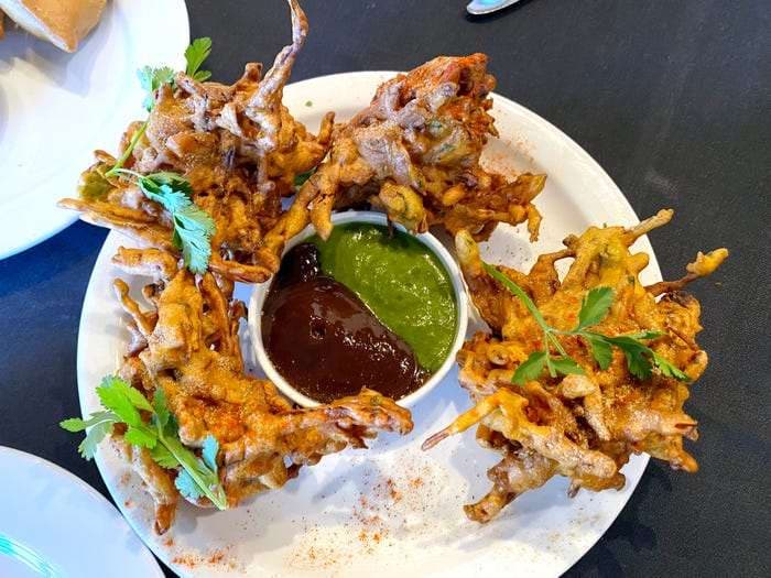 Plate of Nepali fritters with green and dark dipping sauces – achaar somar sauce Sherpa condiments in Toronto