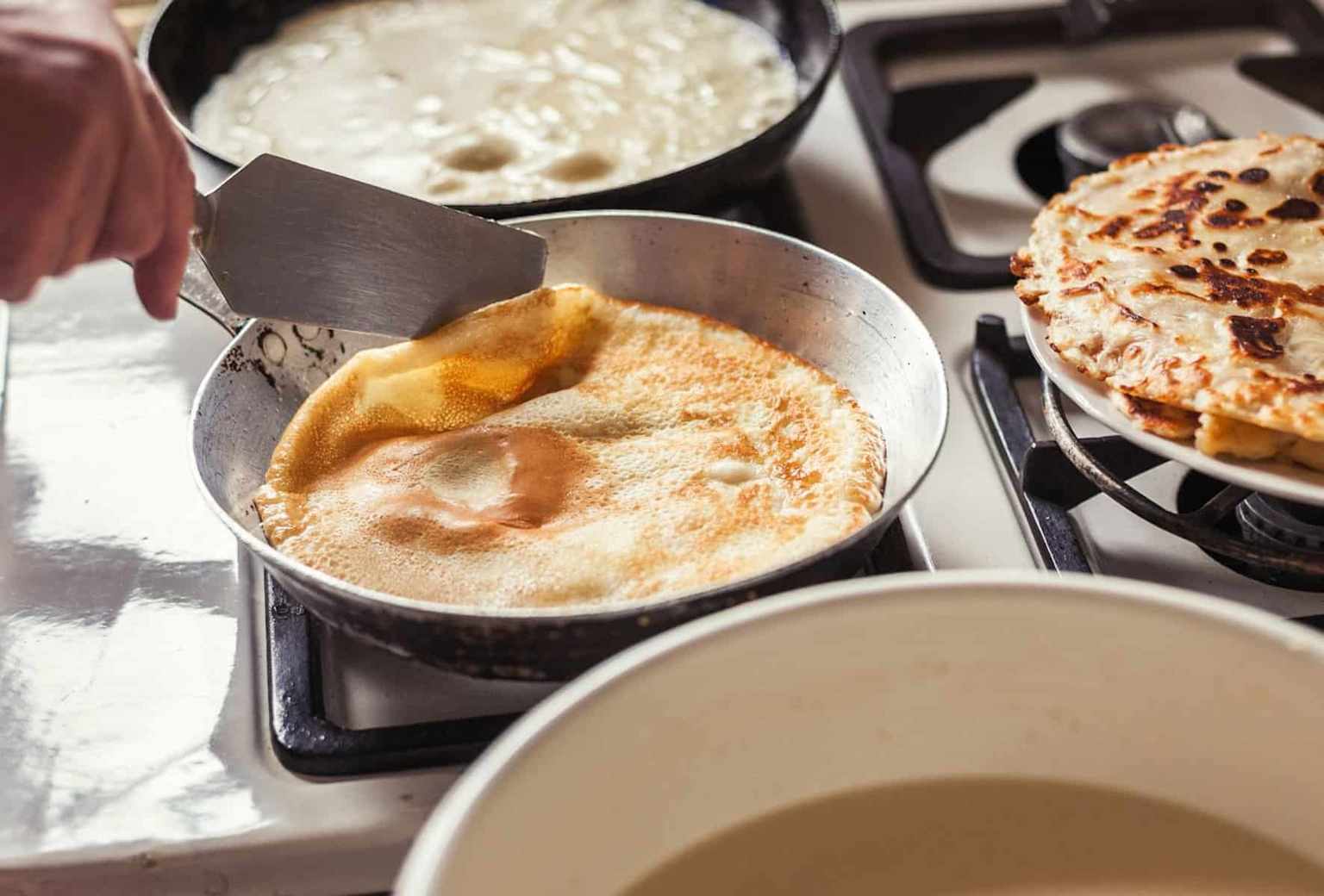 Hand flipping a golden-brown riki kur potato pancake in a pan – cooking Sherpa food in the GTA